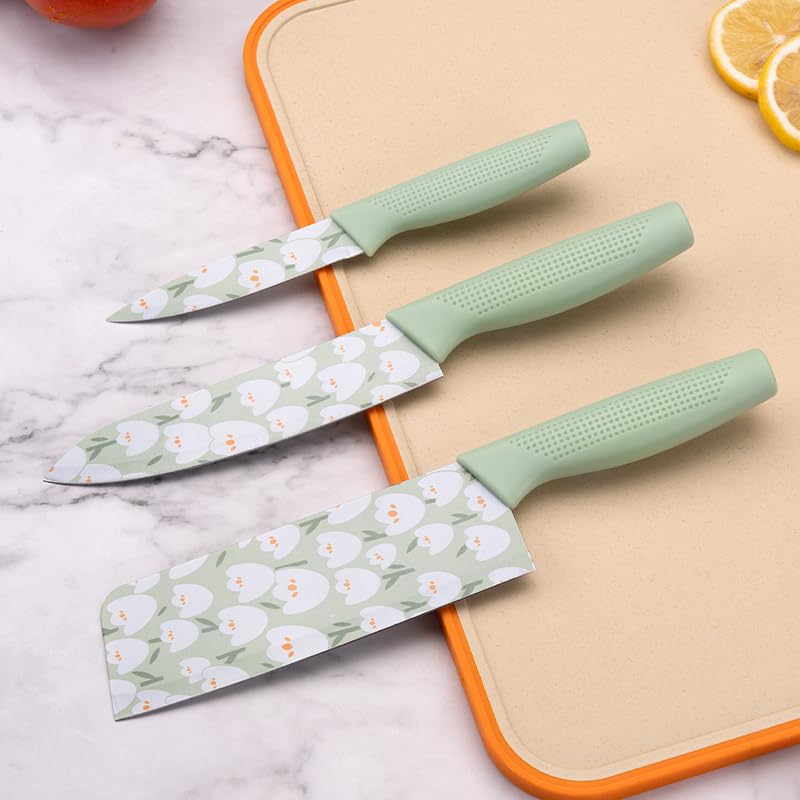 Three knives with floral patterns on green handles on a marble surface.