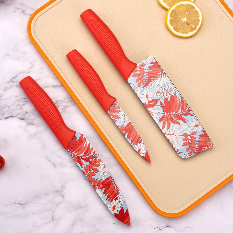Two red-handled knives with floral patterns on a beige cutting board with lemon slices.